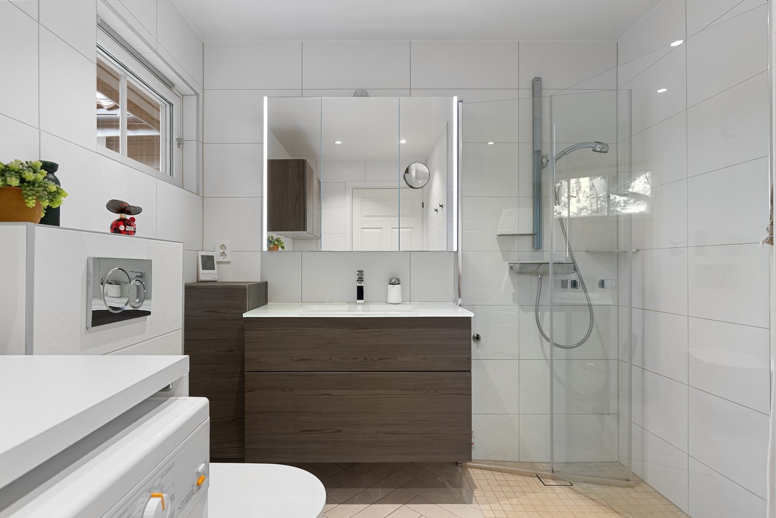 Delikat baderom oppusset i 2020 med flislagte overflater og elektriske varmekabler. Badet har en fin innredning med dusjhjørne, vegghengt klosett og servantr med underskap og speil. Galleribilde