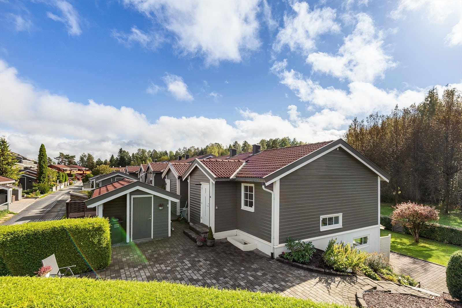 Flott brostensbelagt uteplass på forsiden av huset med tilgang til utebod. Galleribilde