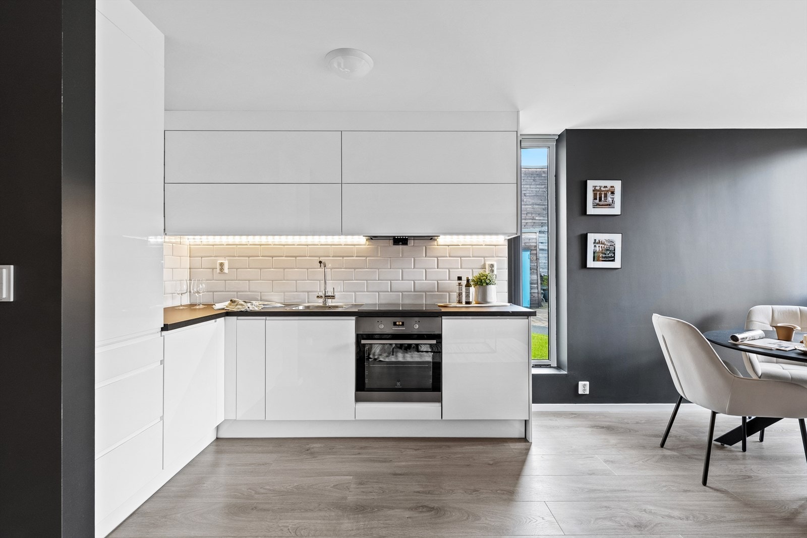 Stilrent kjøkken i åpen løsning mot stue. Kjøkkenet har innredning med glatte fronter og benkeplaten er av laminat. Det er integrert koketopp, stekeovn, kjøl-/fryse-skap og oppvaskmaskin. Galleribilde