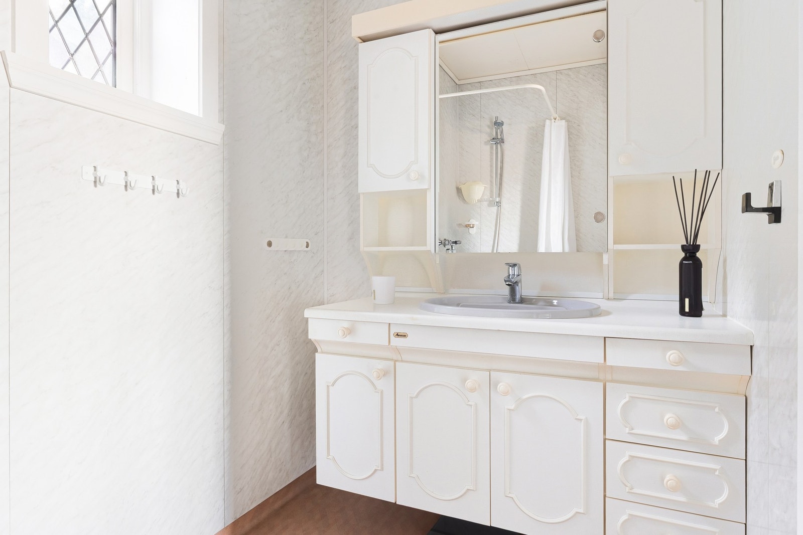 Badet har vinylbelegg på gulvet og våtromsplater på vegger. Det er innredet med baderomsinnredning, toalett og dusjhjørne med forheng. Galleribilde