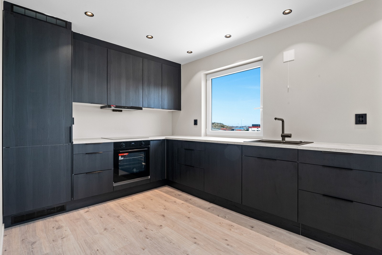 Kjøkkenet har lekker, takhøy innredning i moderne design med mørke fronter Galleribilde