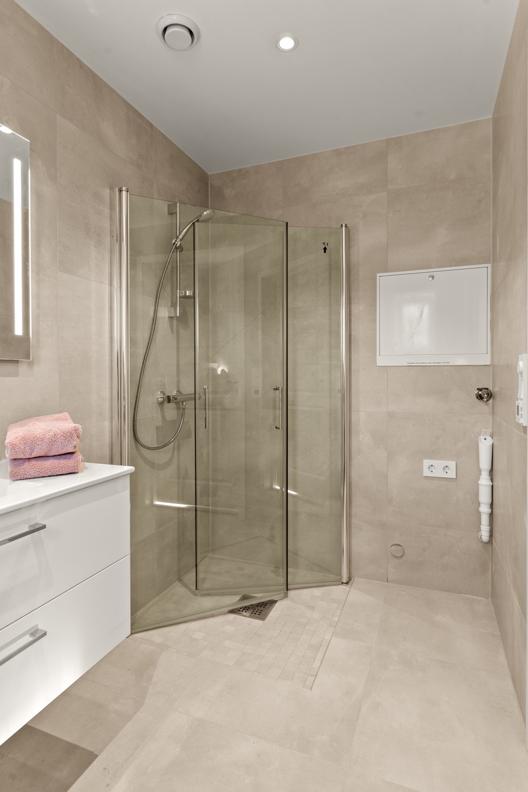 Badet er utstyrt med vegghengt toalett, dusjhjørne og servant med underskap. Det er også opplegg til vaskemaskin Galleribilde