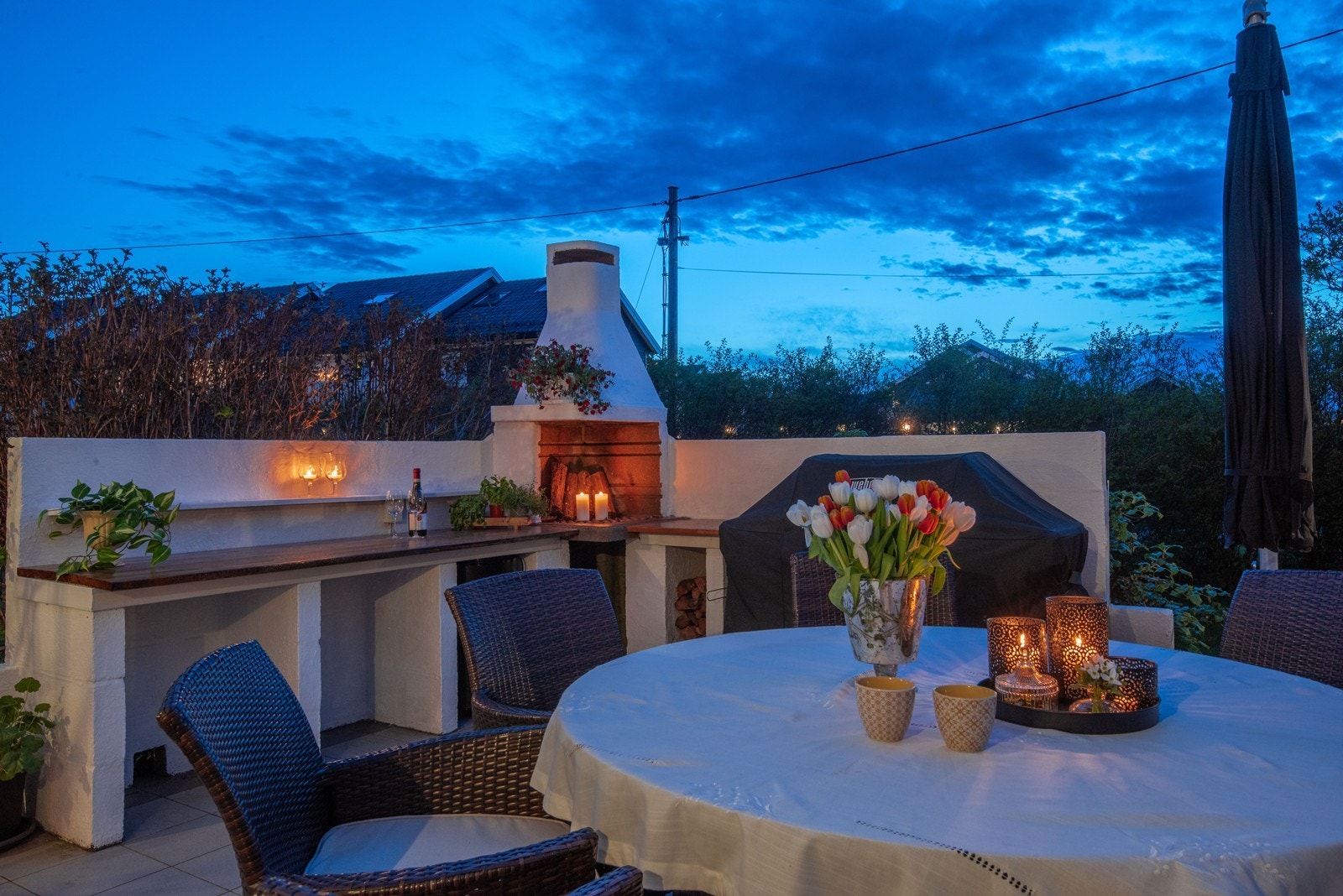 I hjørnet på terrasse er et utekjøkken med benkeplate i tre, hyllerom, åpen peis og plass til grill. Galleribilde