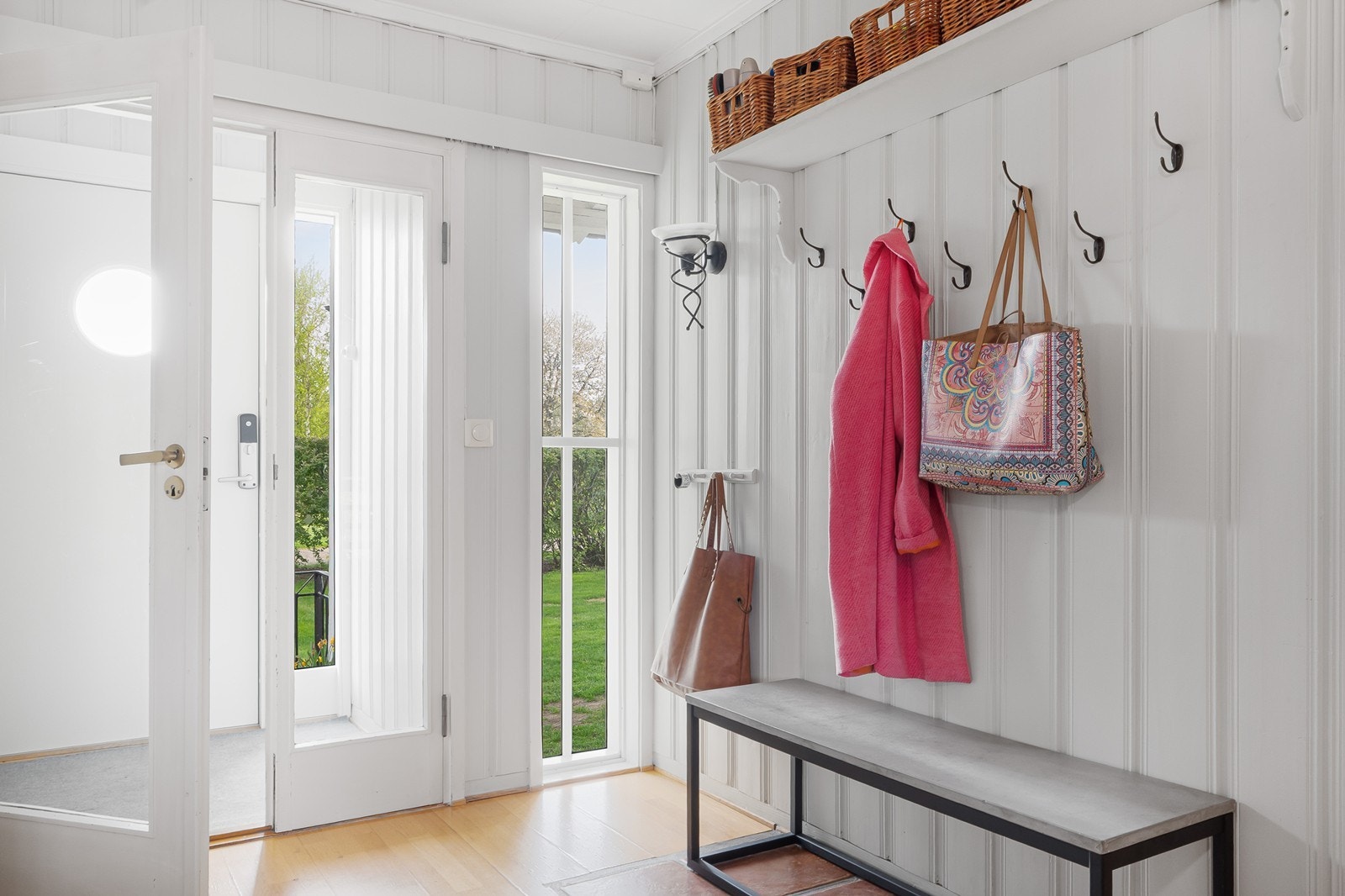 Videre fører vindfang til en lys hall med knagger og hyller. Galleribilde