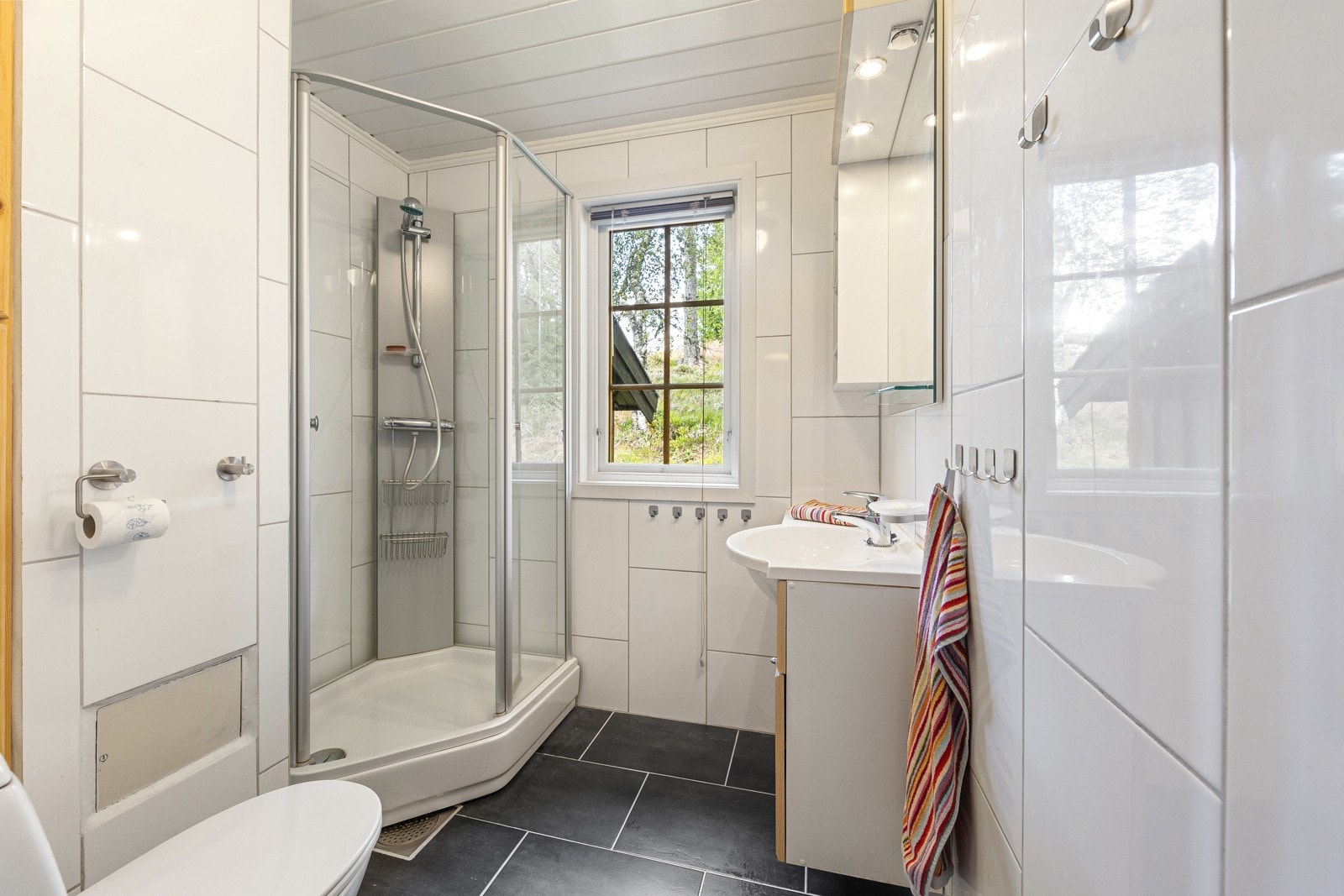 Flott baderom fra 2017 som er innredet med dusjkabinett, servant montert i baderomsinnredning og toalett. Galleribilde