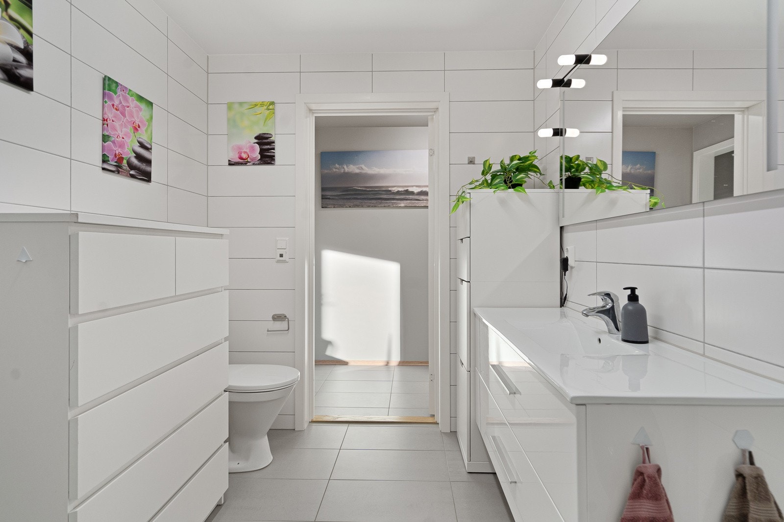 Badet er innredet med dusjhjørne, servant med skuffer og speil, samt toalett og opplegg til vaskemaskin i en nisjeløsning Galleribilde