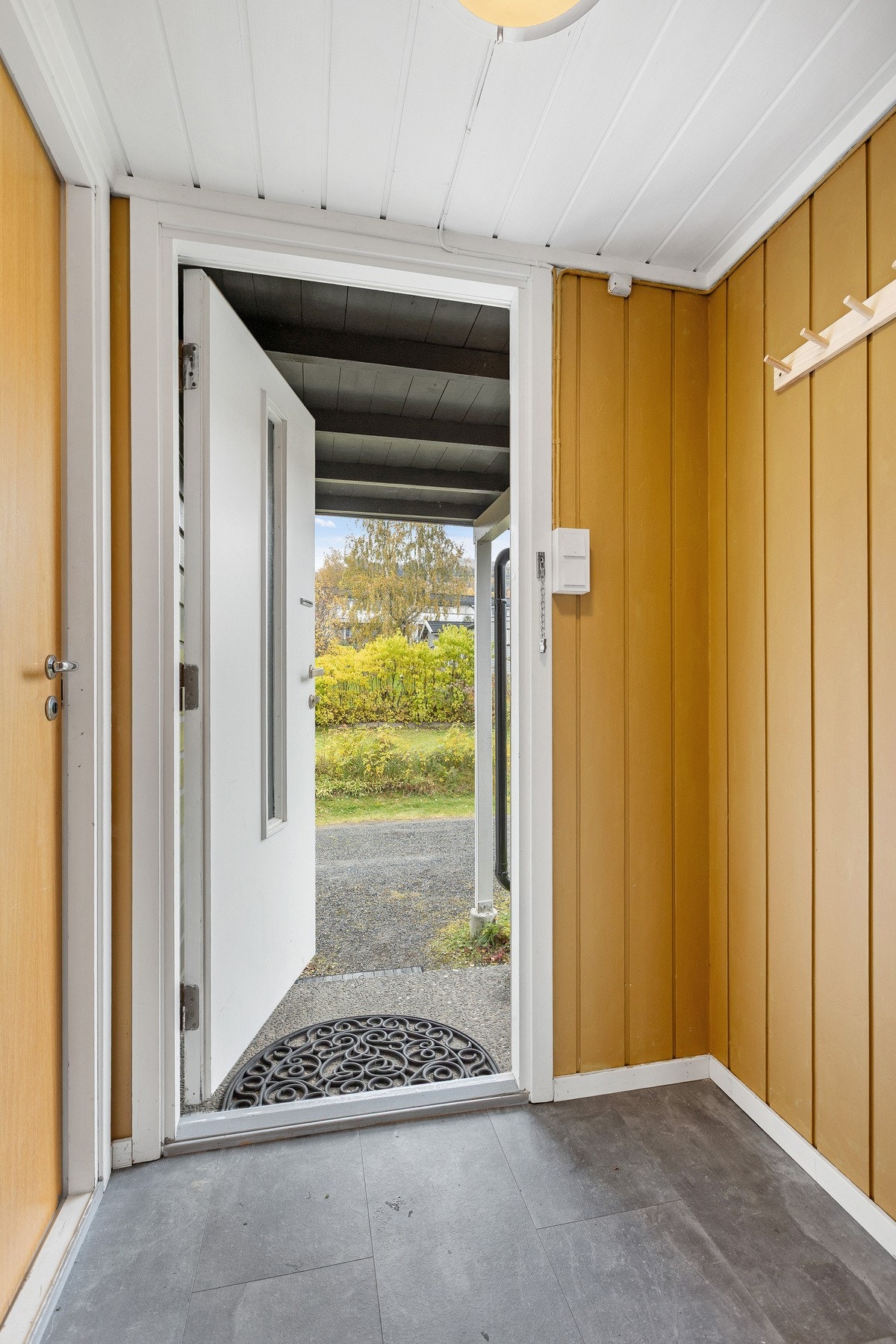 Overbygd inngangsparti med plass til yttertøy og sko - en praktisk velkomst til boligen. Galleribilde