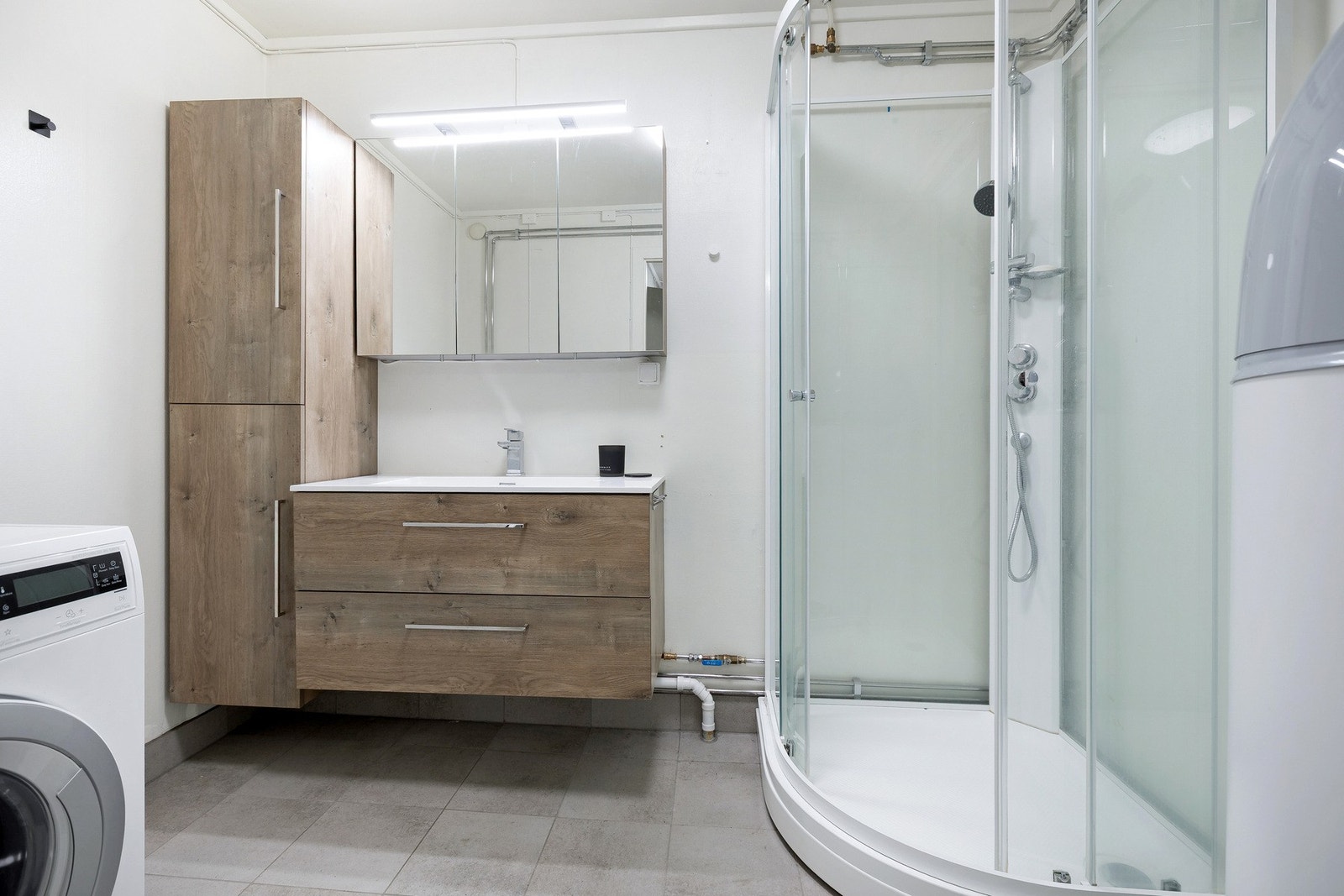 Delikat baderom med moderne innredning, dusjkabinett og plass til vaskemaskin. Galleribilde