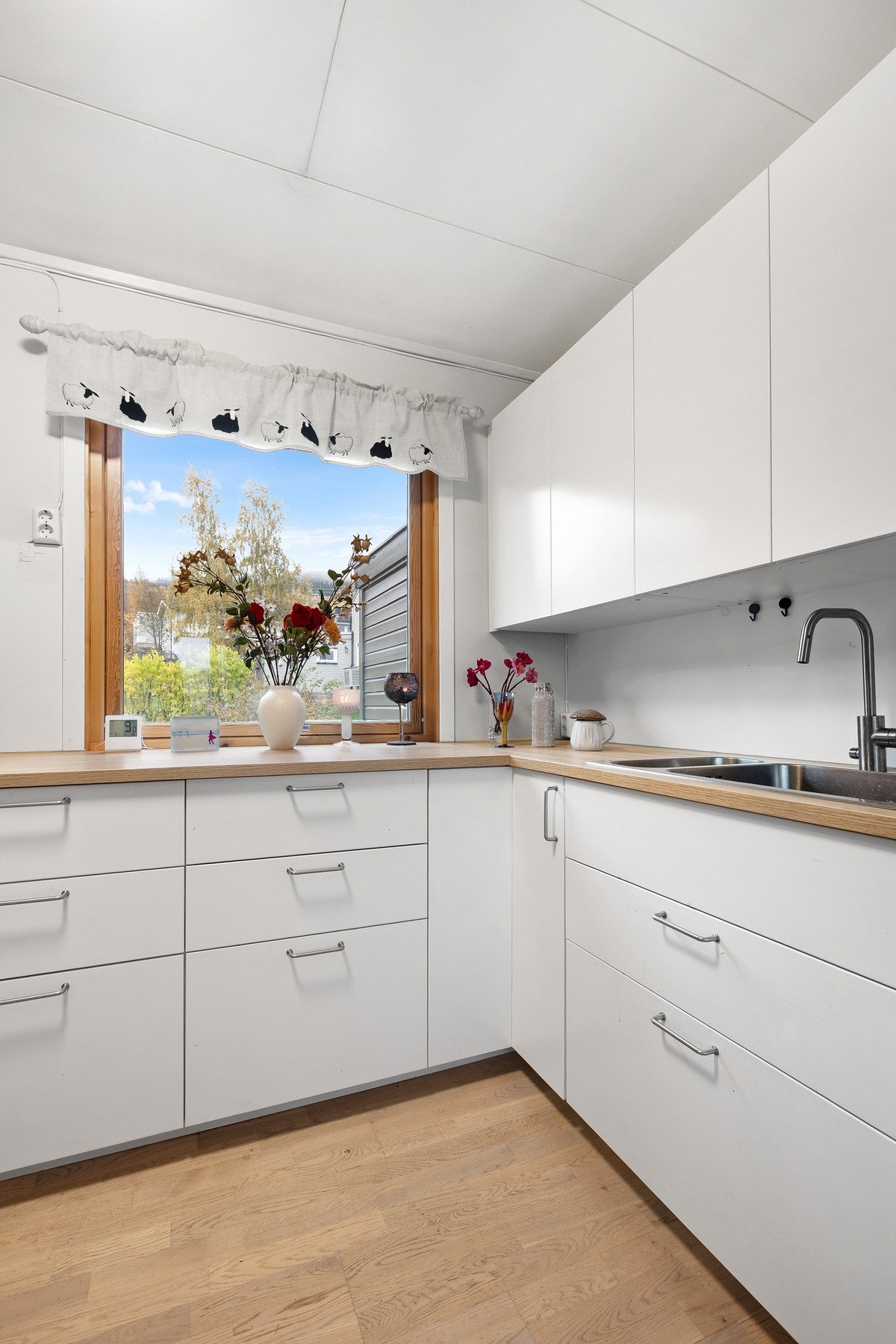 tilrent kjøkken i lyse farger med vindu som slipper inn rikelig dagslys. Galleribilde