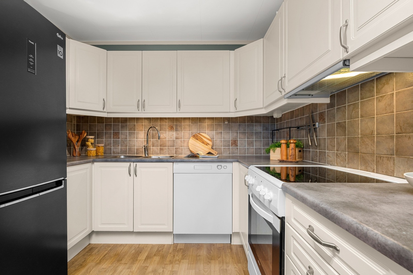 Innholdsrikt kjøkken med frittstående hvitevarer Galleribilde