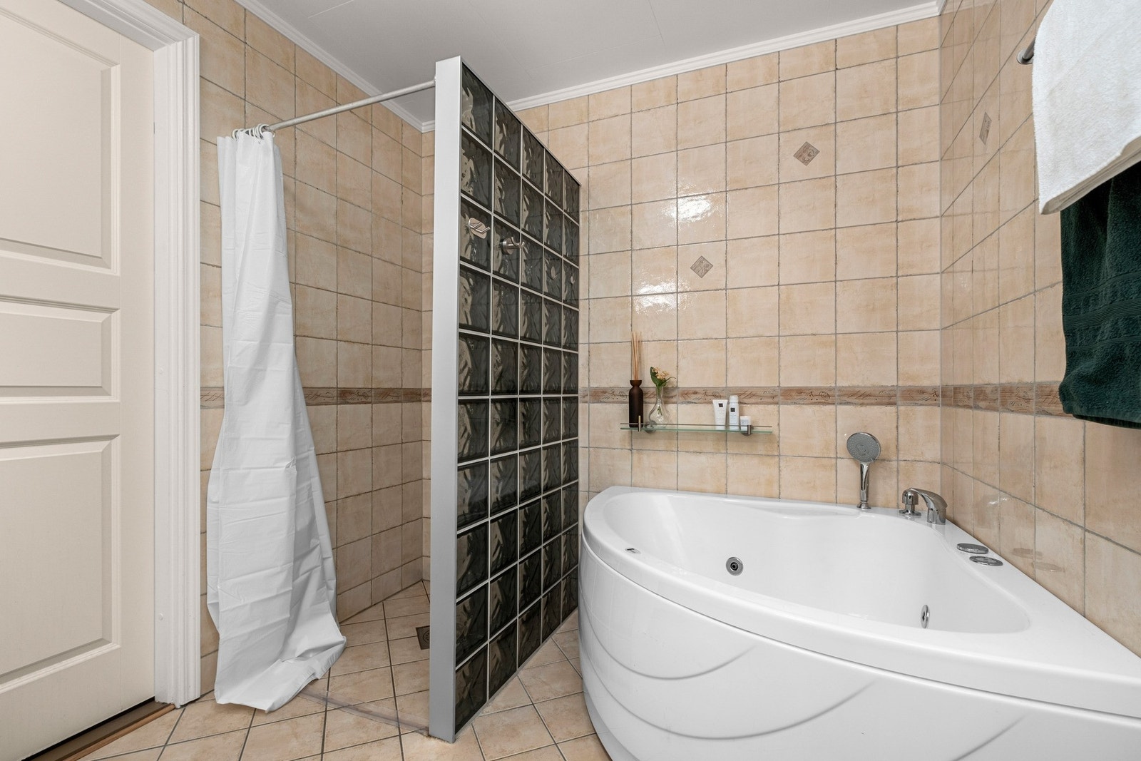 Badet er utstyrt med badekar, dusjhjørne, gulvmontert toalett og veggmontert servantinnredning. Galleribilde