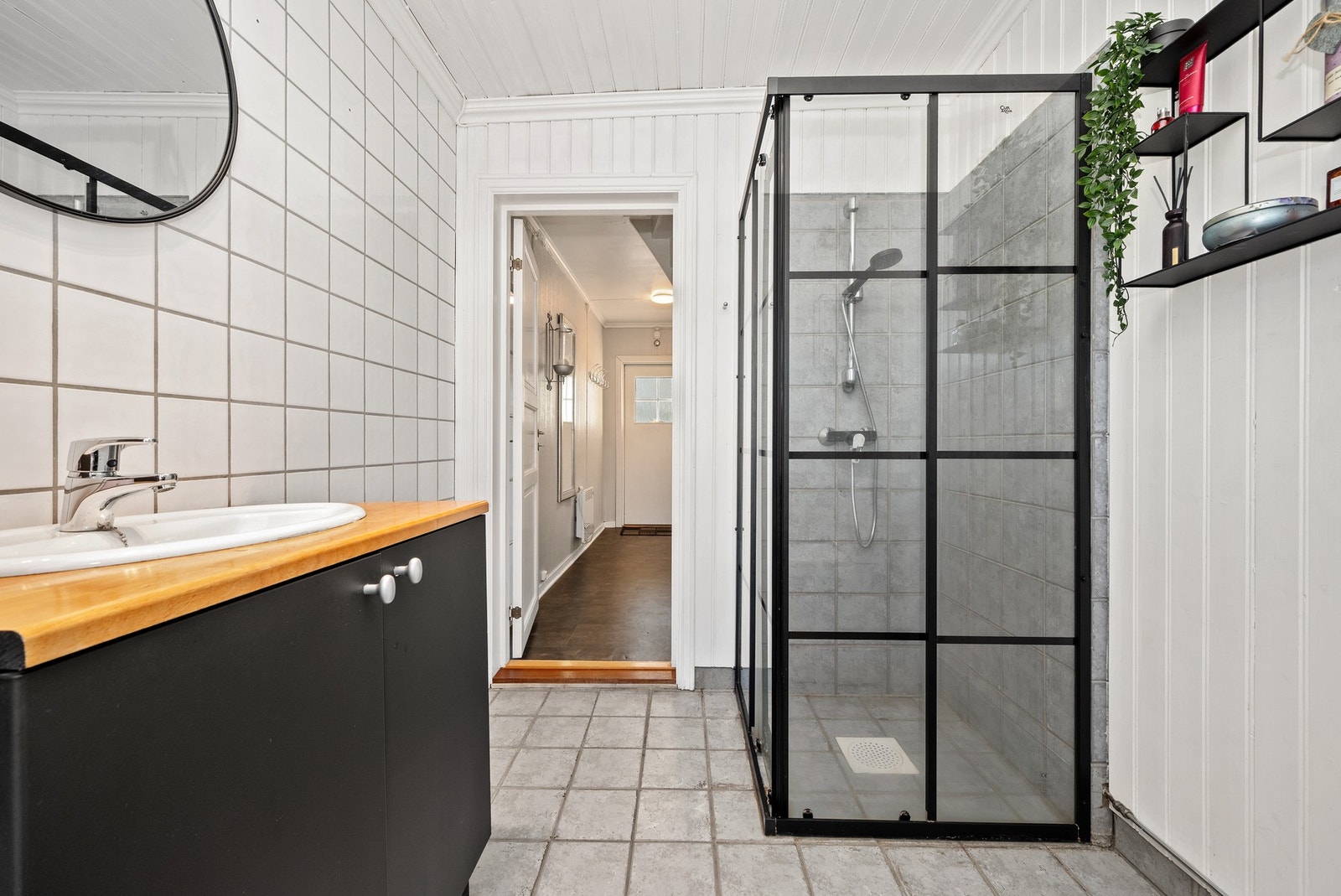 Badet har god skapplass, og et dusjhjørne er utstyrt med innfellbare glassdører i sort innramming. Galleribilde