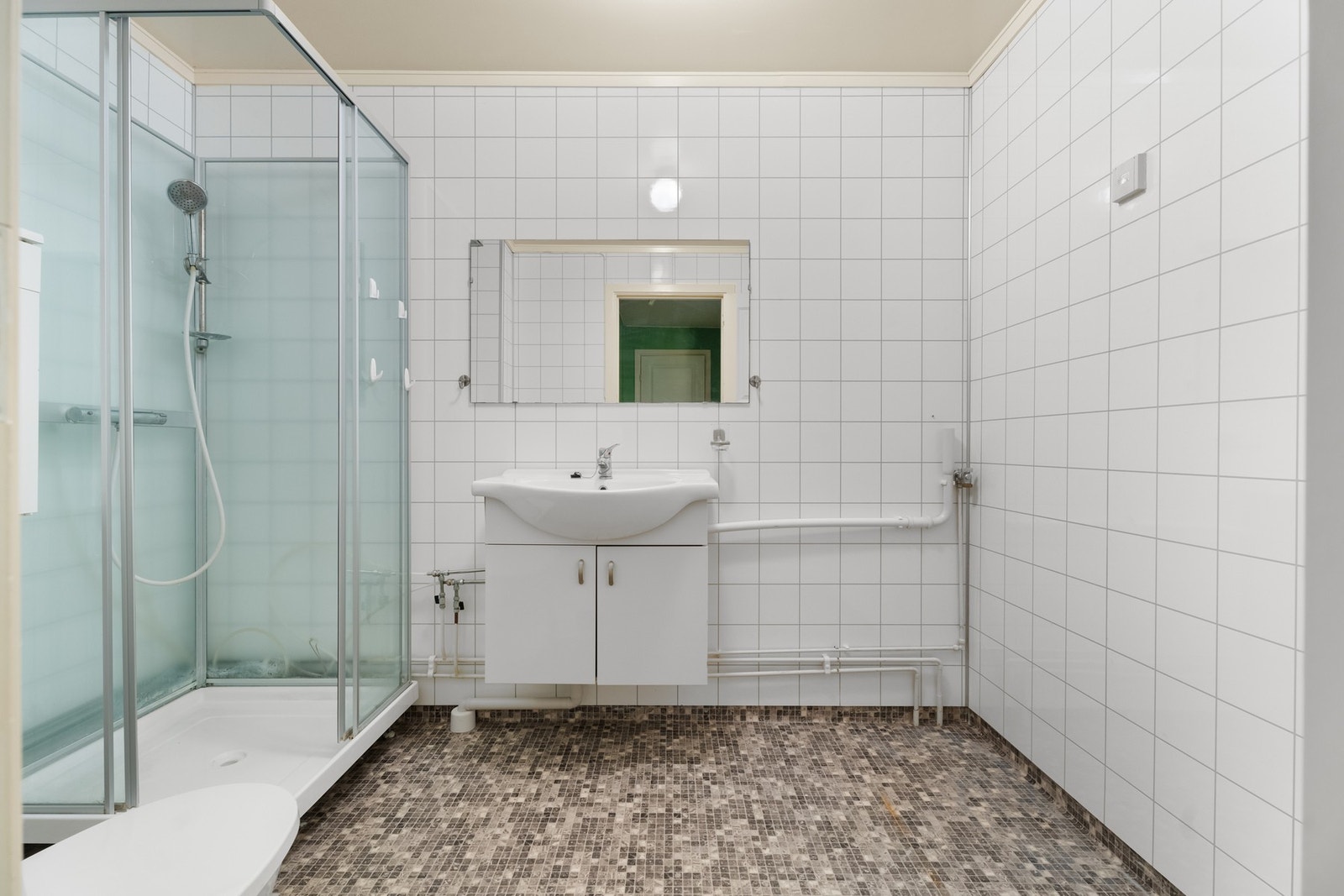 Baderomsinnredningen har hvite fronter og består av en heldekkende servant på en skapseksjon, og over er det et stort speil. Galleribilde