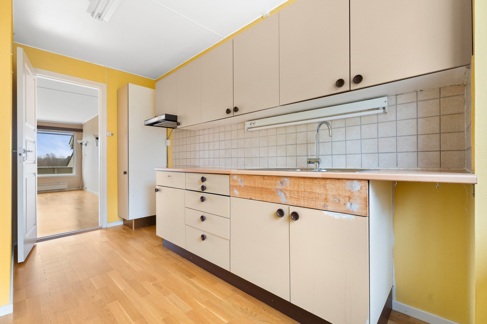 Innredningen har beige, glatte fronter og lys laminatbenkeplate med nedfelt kum i stål. Galleribilde