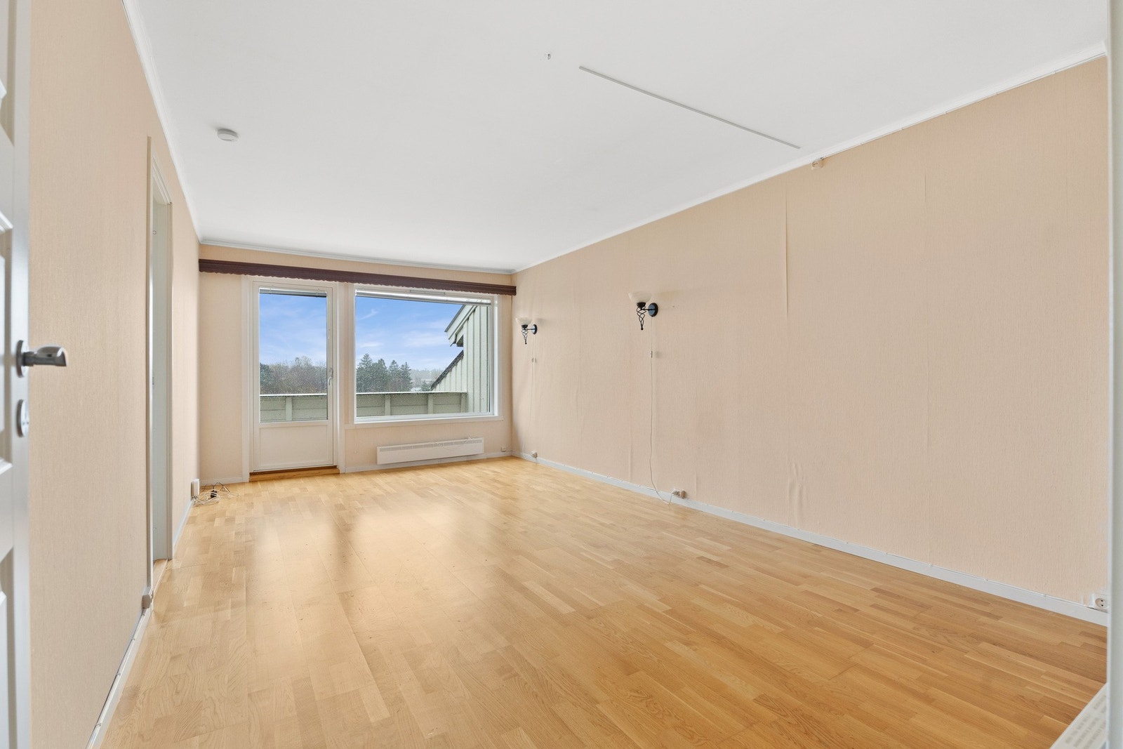 Stuen oppleves som luftig og pen, og rommet er holdt i en stilren kombinasjon med beigemalte vegger mot gyllent, trestavs parkettgulv Galleribilde