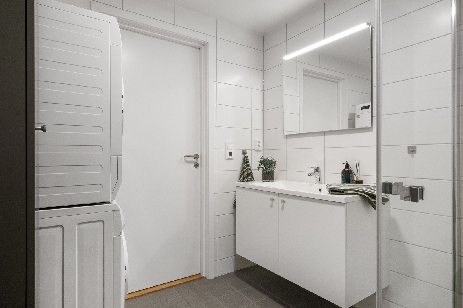 Badet er innredet med vegghengt toalett, dusjhjørne, baderomsinnredning og opplegg for vaskemaskin. Galleribilde