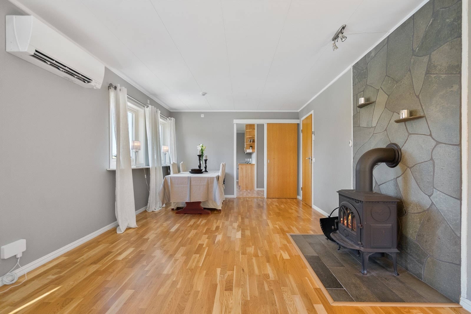 Stuen byr på varme toner fra tregulv og en lun vedovn som skaper et naturlig samlingspunkt Galleribilde