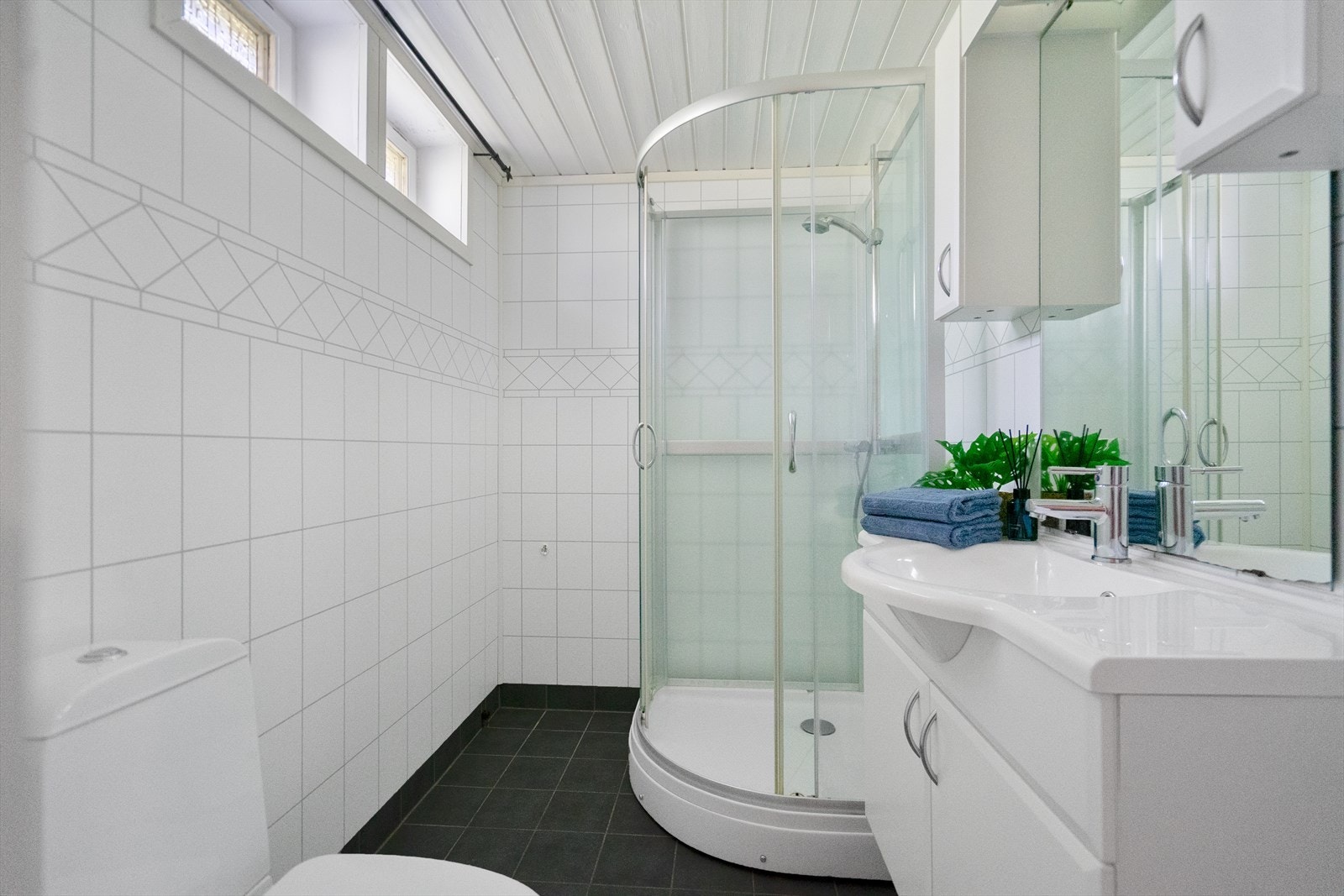 Badet i 1.etasje er utstyrt med baderomsinnredning, oppbevarings skap- og skuffer, toalett og dusj Galleribilde