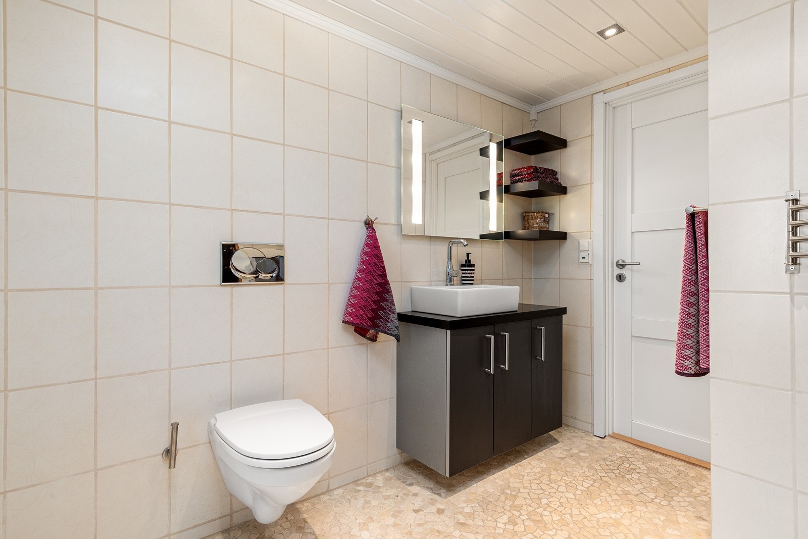 Rommet er innredet med servant, veggmontert toalett, dusjhjørne med glassvegger og opplegg for vaskemaskin. Galleribilde