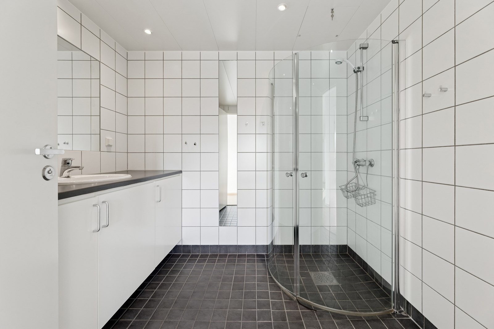 Badet er tidløst innredet med grå fliser på gulv og hvite fliser på vegg. I gulvet har man også varmekabler for ekstra komfort. Galleribilde