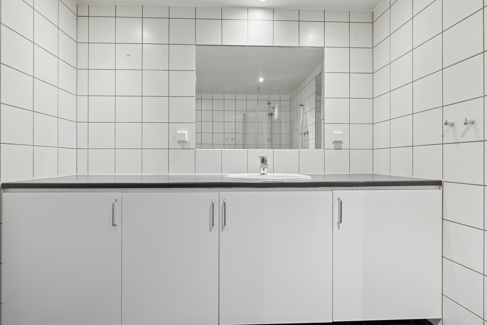 Badet er ellers utstyrt med dusjhjørne, vegghengt toalett og baderomsinnredning med nedfelt servant. Galleribilde