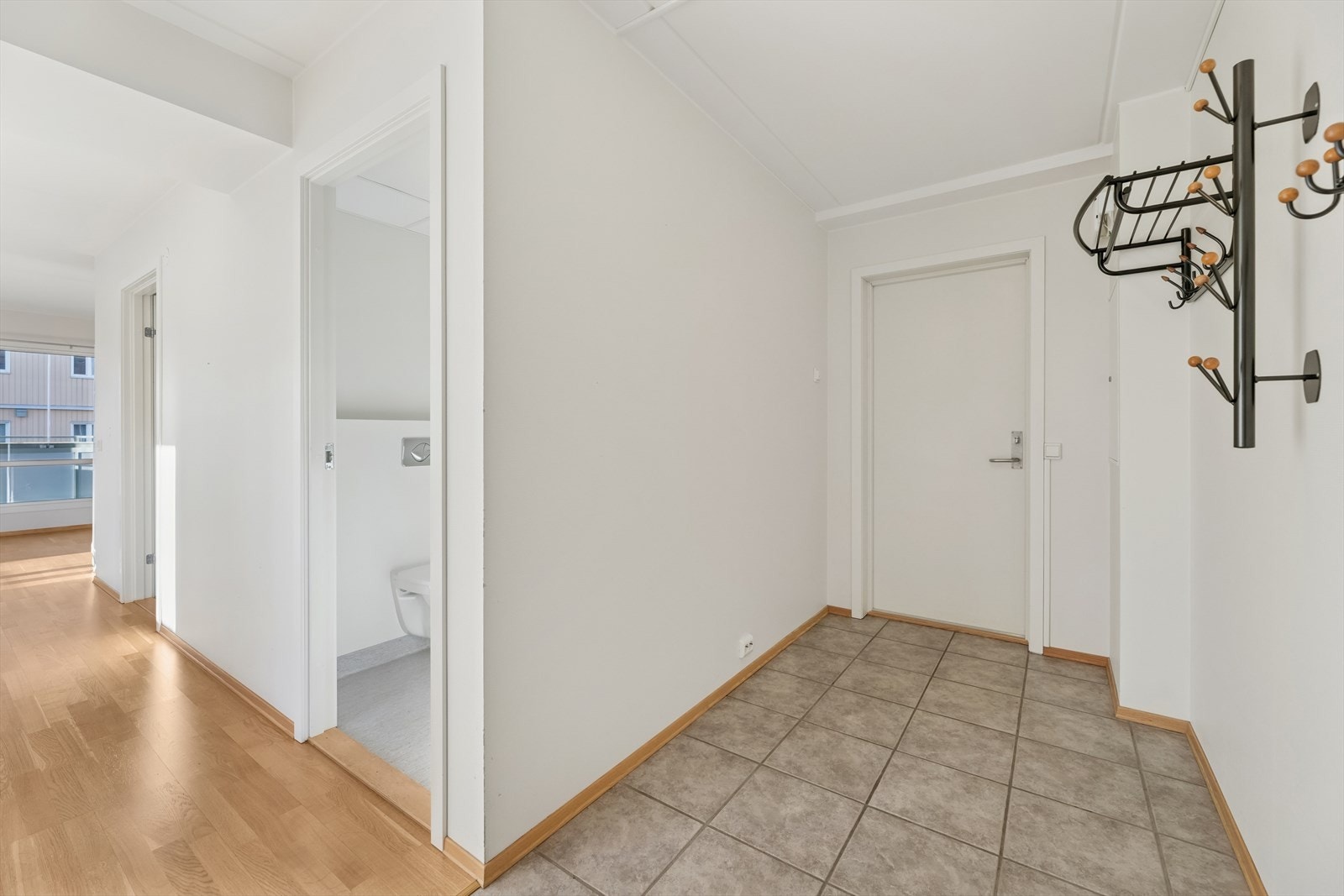 lRomslig entré som er praktisk innredet med flislagt gulv. Her har man god plass til å henge fra seg yttertøy og sko. Galleribilde