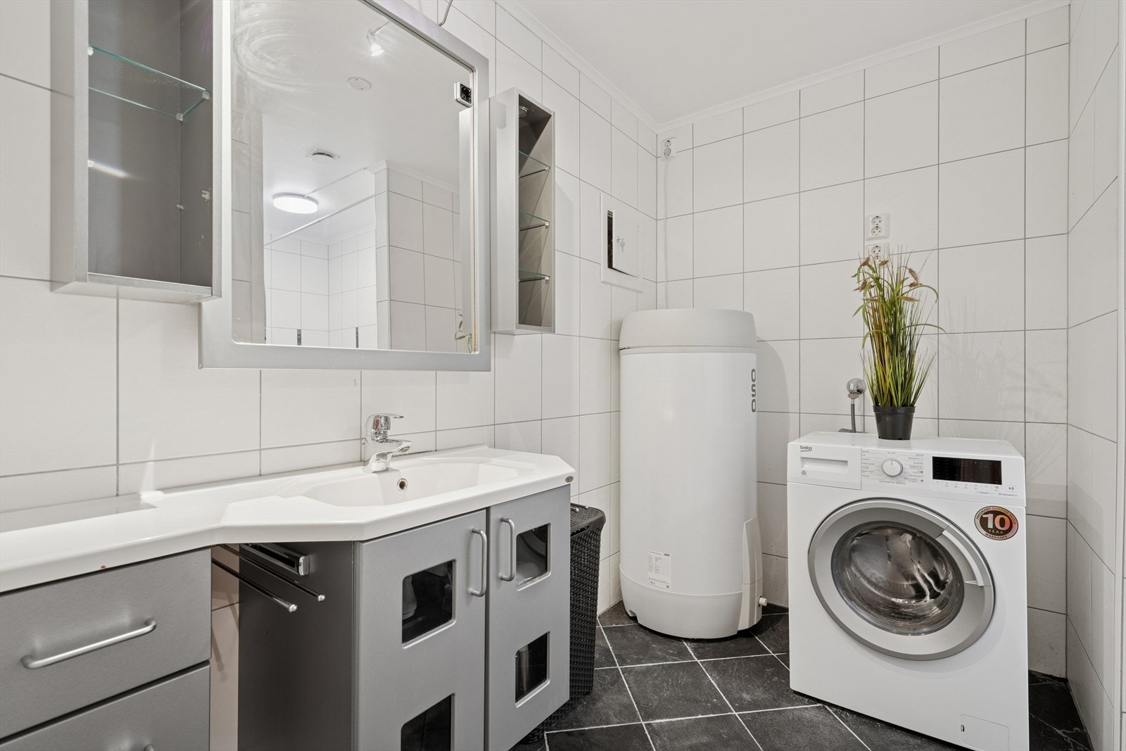 Badet har mørke gulvfliser m/varmekabler under og hvite veggfliser Galleribilde