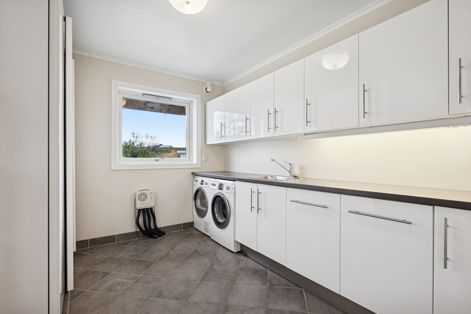 Praktisk vaskerom med smart innredning og opplegg for vaskemaskin/tørketrommel. Varmekabler i gulv. Galleribilde