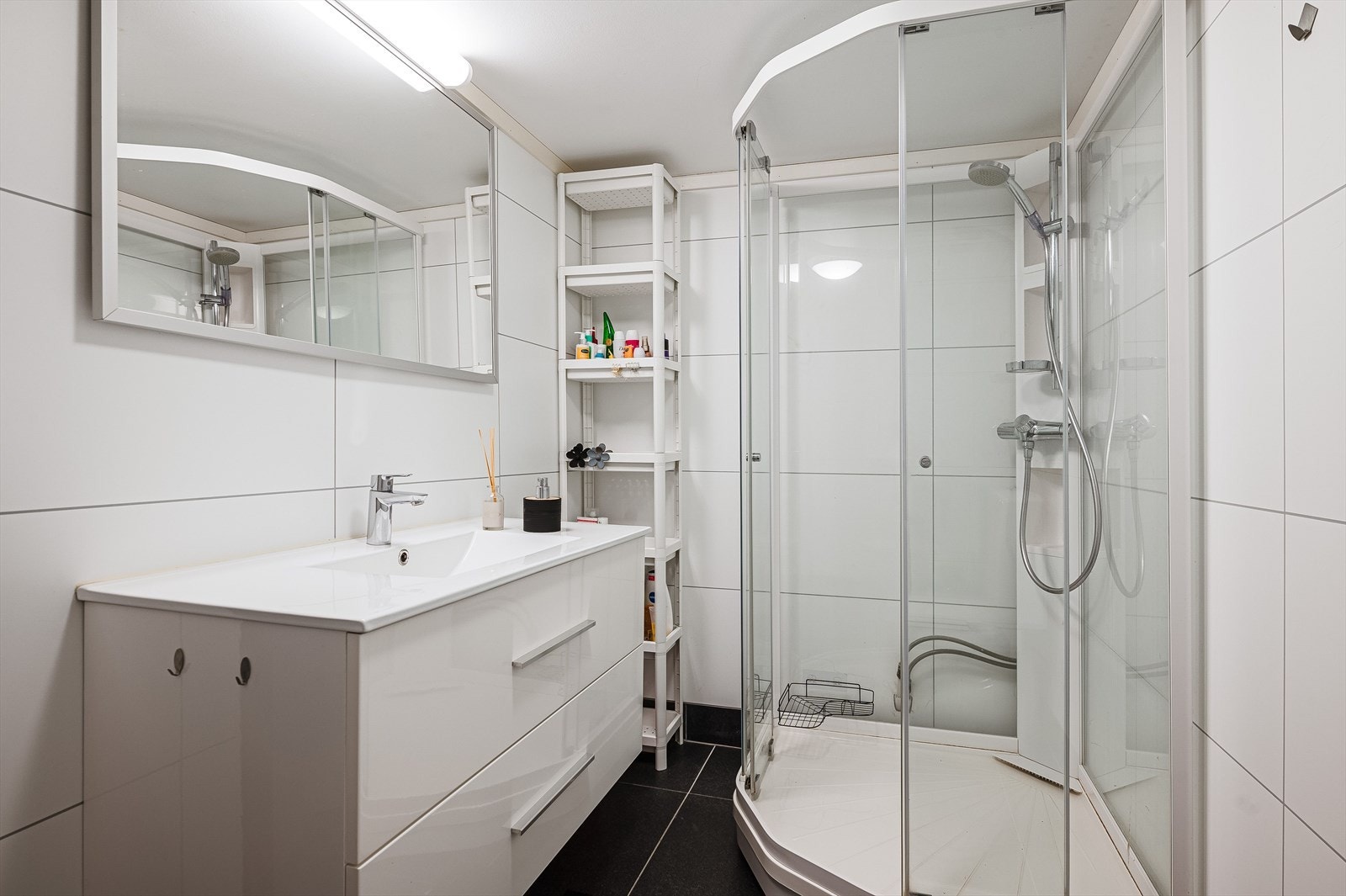 Leilighetens baderom har en pen fremtoning med mørke gulvfliser med varmekabler under, samt store hvite veggfliser. Moderne innredning med heldekkende servant, samt dusjkabinett og wc. Galleribilde