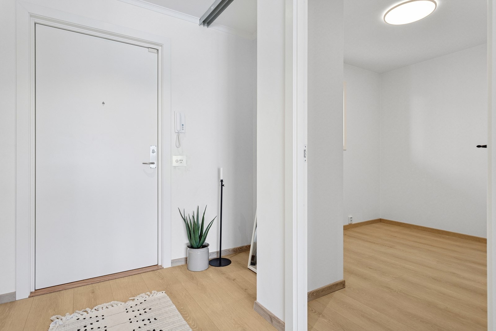 Lysmalt entré på ca 4,3 m² som har "innhuk" med plass for skyvedørsgarderobe. Porttelefon. Velkommen inn! Galleribilde