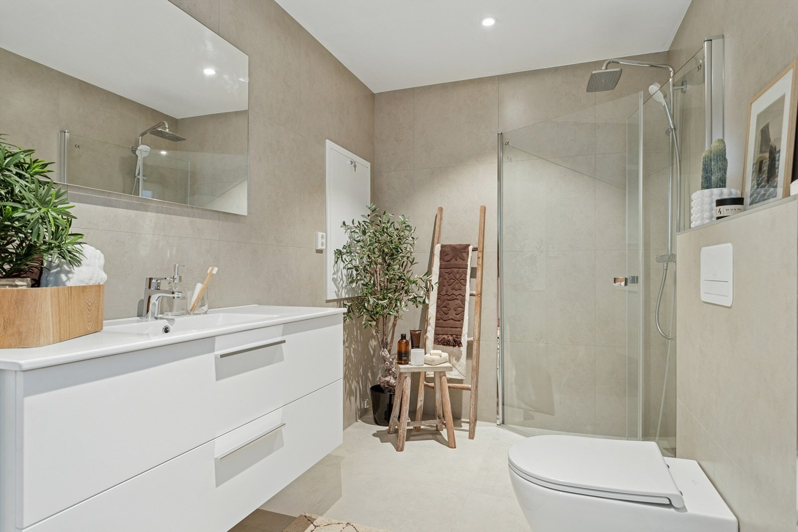 Baderommet er ca 5,7 m² og har flislagte gulv og vegger samt malt slett himling med innfelte downlights. Innfellbare dusjvegger av glass og vegghengt toalett. Galleribilde