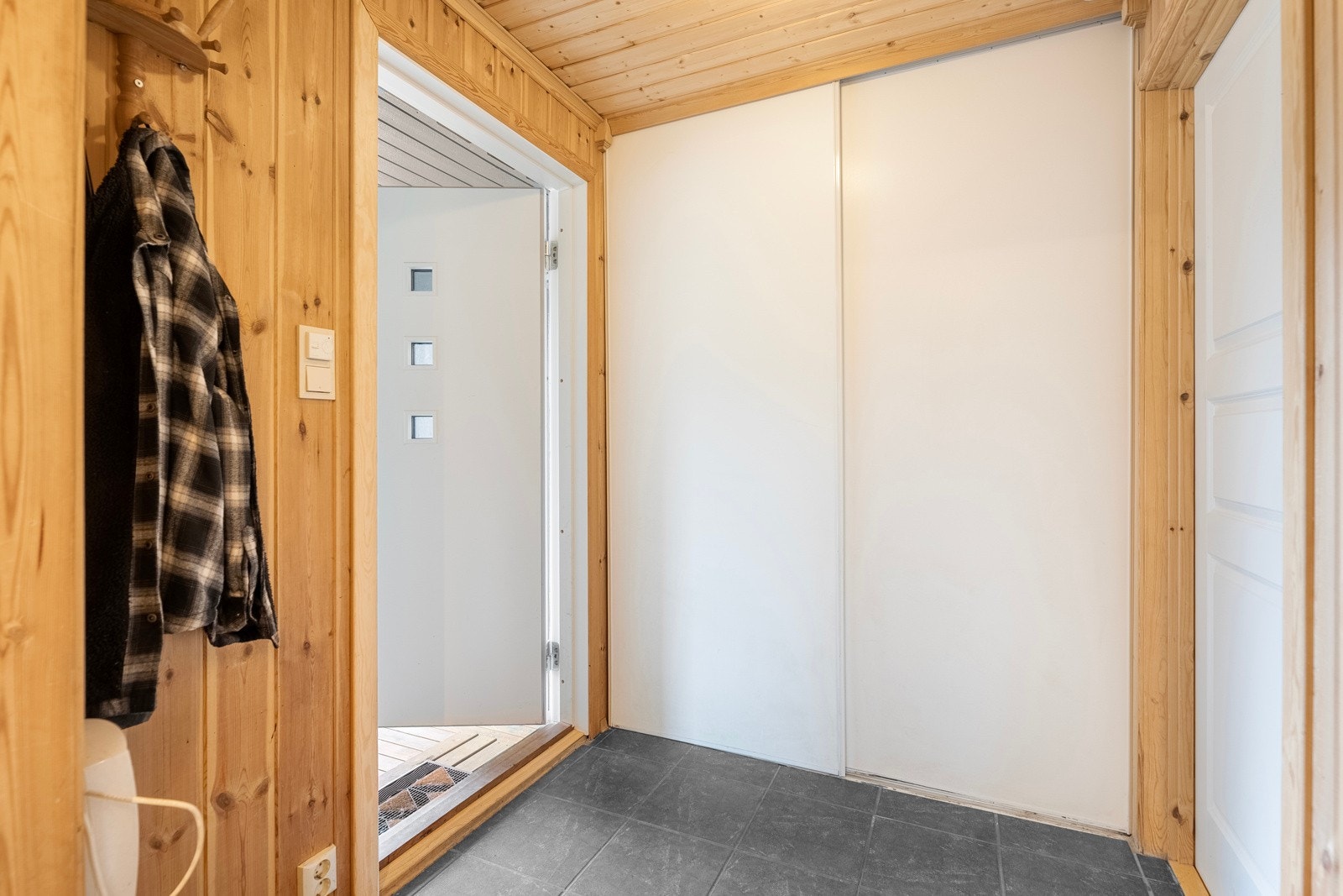 Entre med panel på vegger og fliser på gulv. Fin avsatt plass til å henge av seg klærne. Galleribilde