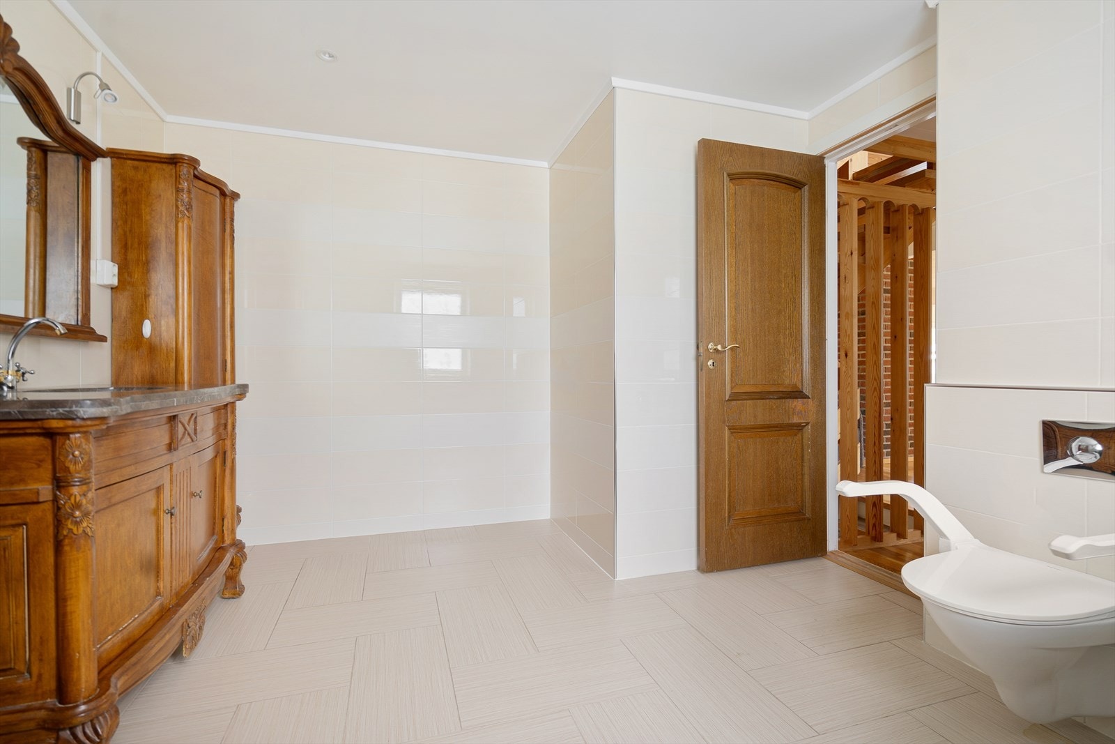 Stort og innbydende bad med lyse fliser og klassiske trefinerte dører som gir et elegant preg Galleribilde