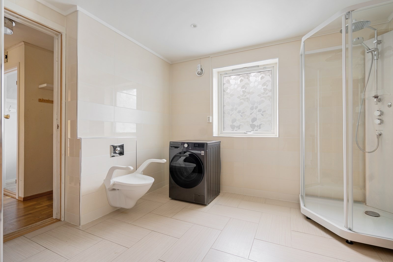 God plass og praktiske løsninger med både dusjkabinett og opplegg for vaskemaskin. Et rom som kombinerer funksjonalitet og stil Galleribilde