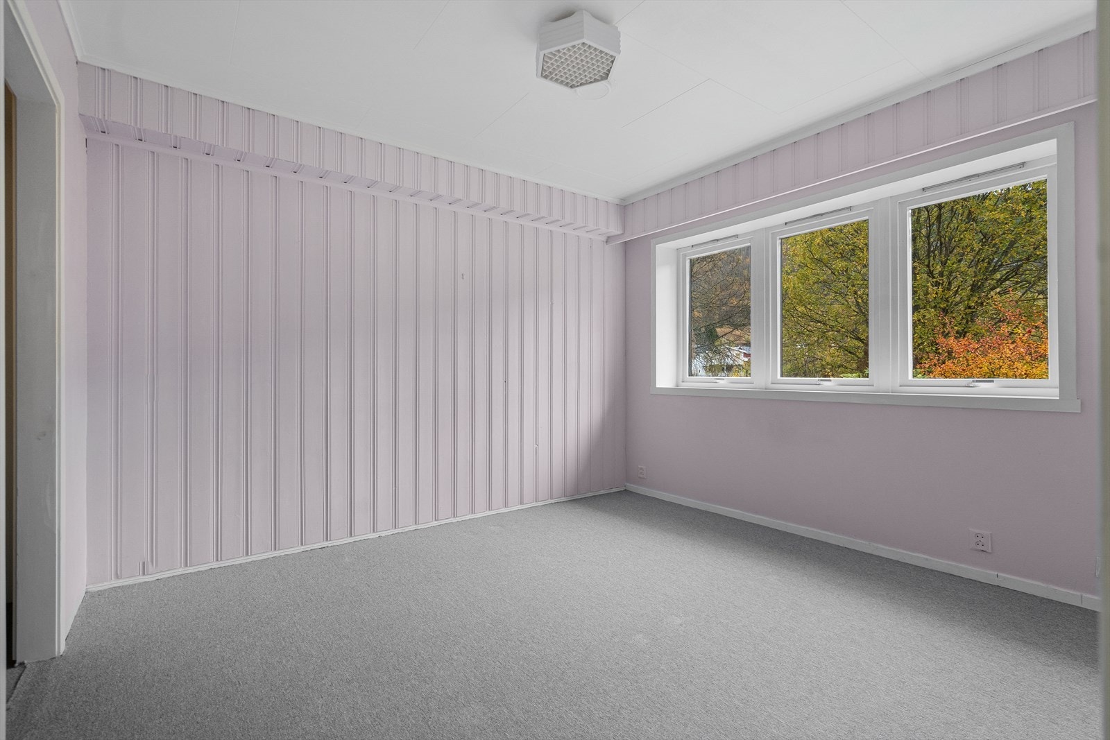 Et trivelig soverom med flere vindu som slipper inn rikelig med dagslys og gir utsyn mot hagen Galleribilde