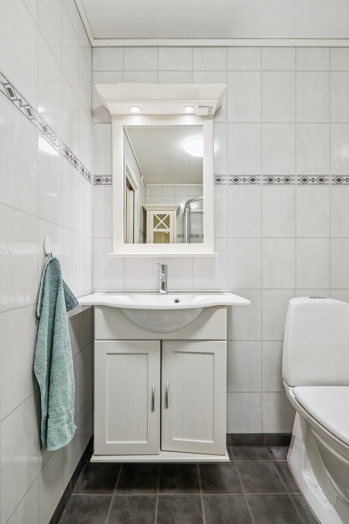 Innredning med profilerte skapfronter. Helstøpt servant og speil med belysning over. Galleribilde