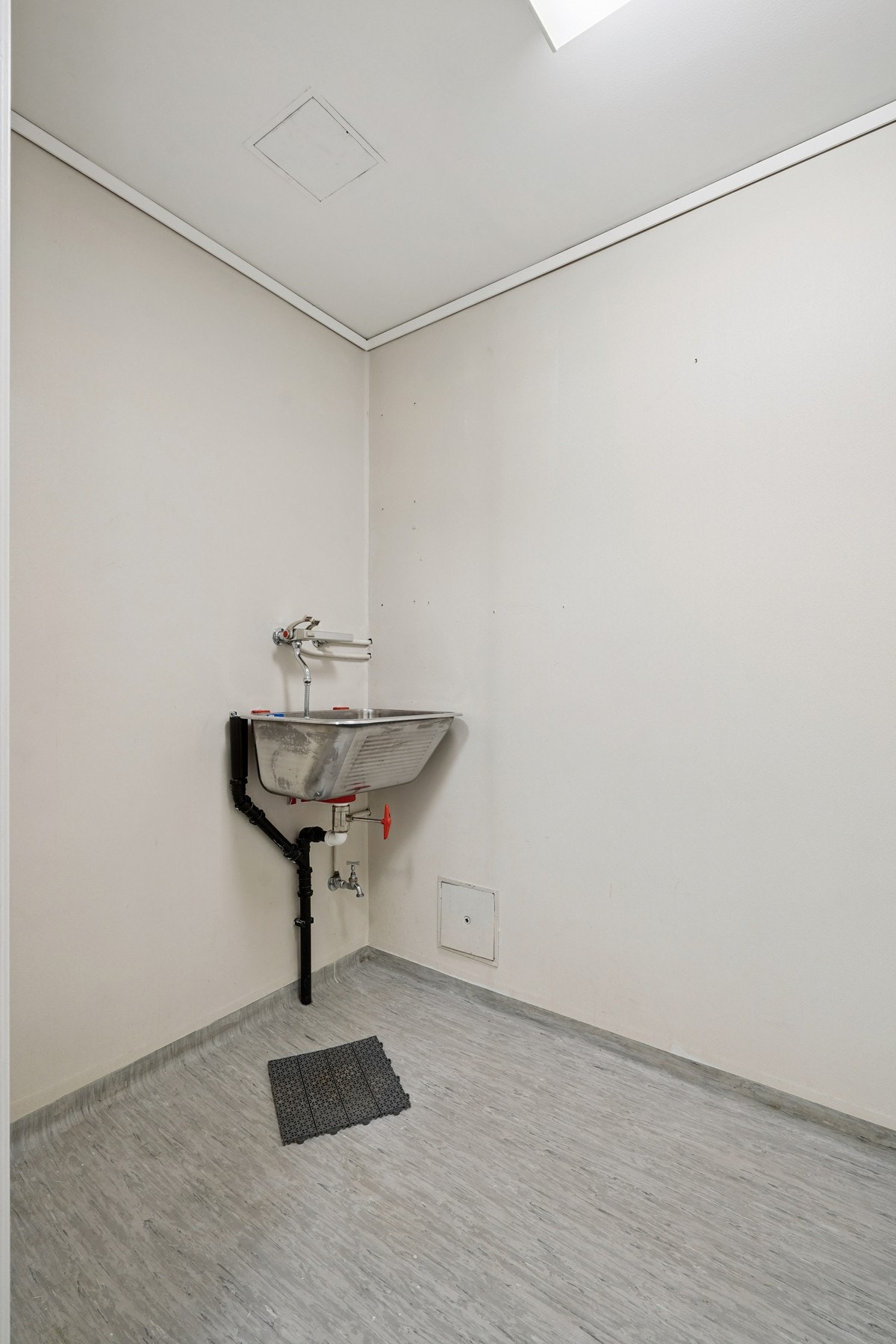 Vaskerom med utslagsvask og opplegg for vaskemaskin. Belegg på gulvet og malte vegger. Galleribilde