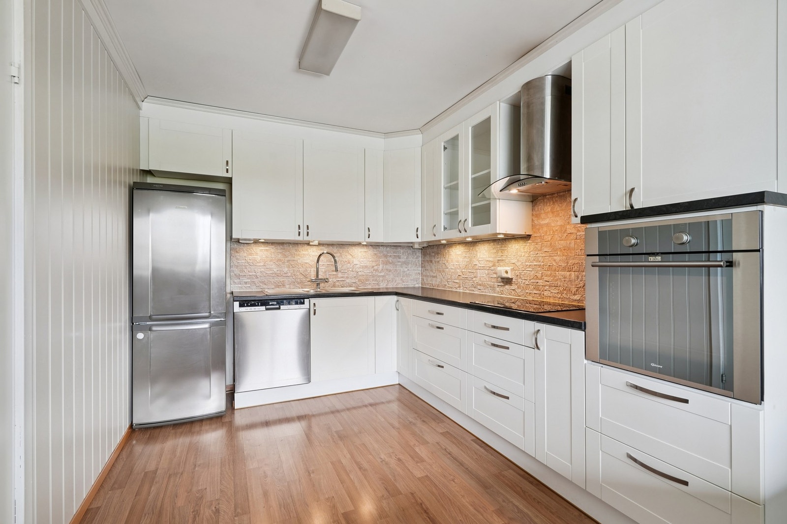 Kjøkkeninnredning med hvite profilerte fronter og håndtak. Galleribilde