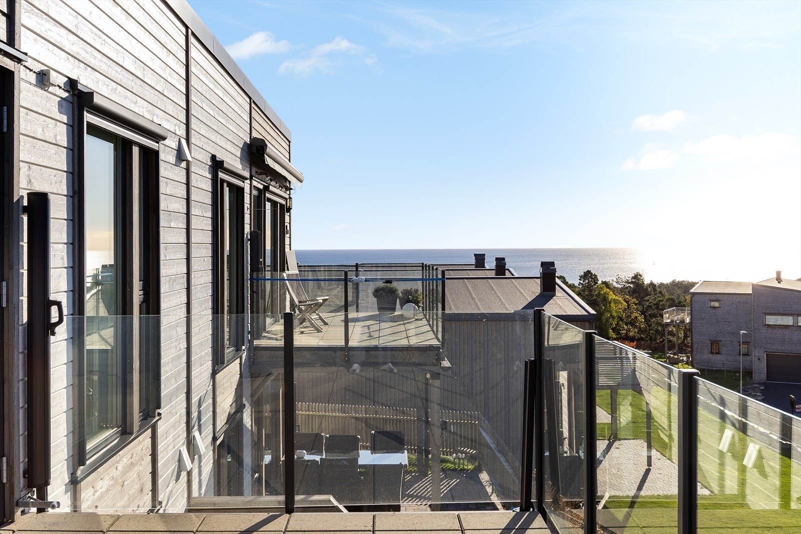 Flott terrasse med glassrekkverk og nydelig sjøutsikt Galleribilde
