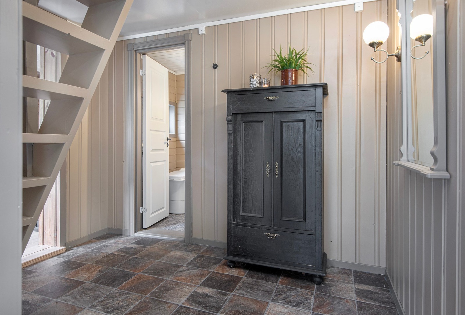 Romslig gang med trapp opp til loftet. Inngang til toalett og kjøkken. Galleribilde