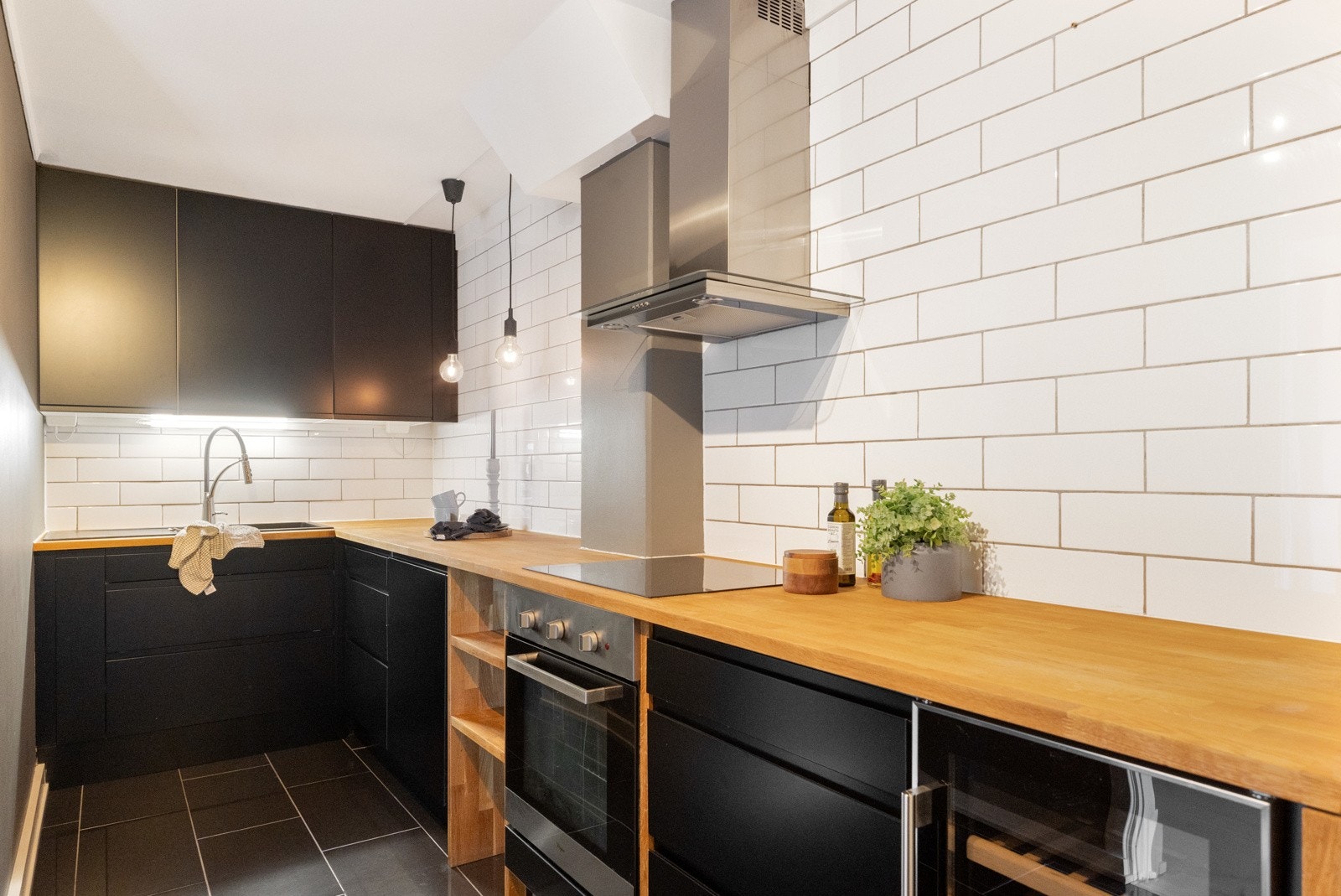 Moderne kjøkken fra Epoc med svarte, glatte fronter og takhøye overskap. Benkeplate i tre. Galleribilde