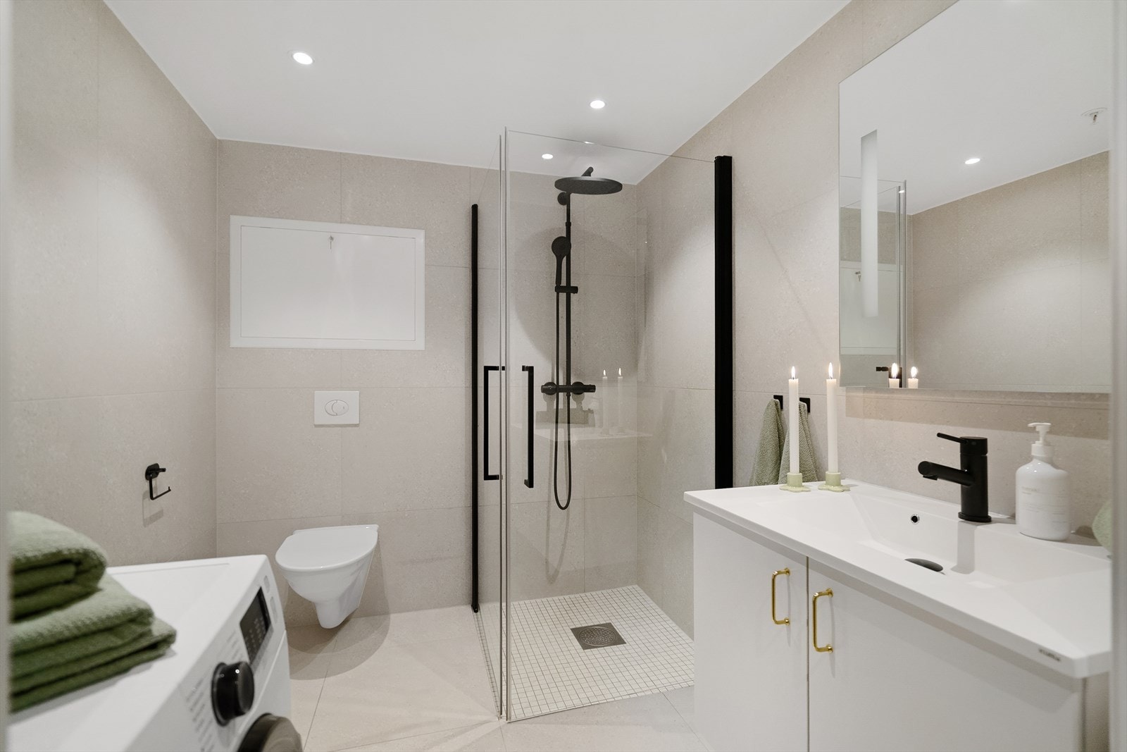 Lyst og elegant bad innredet i nøytrale fargetoner, med stilrene kontraster i sort og messing Galleribilde