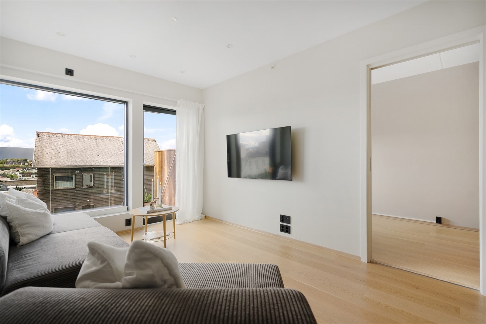 Lys og åpen stue med utgang til balkong og store vindusflater som slipper inn rikelig med dagslys Galleribilde