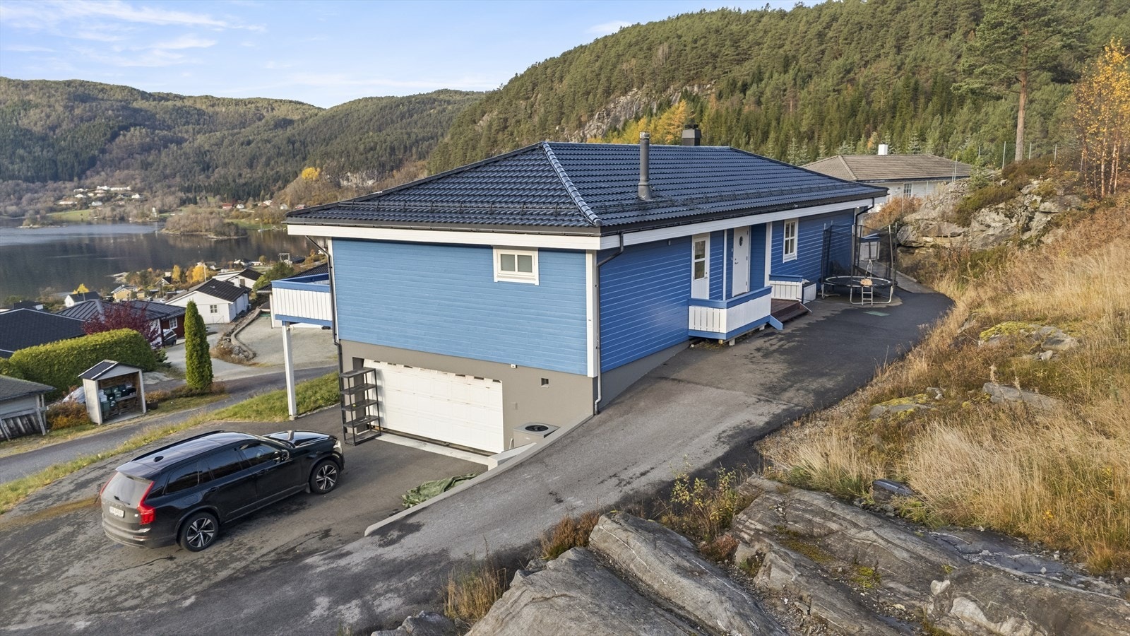 Asfaltert tun med plass til parkering av fleire bilar, samt innkøyring til integrert dobbel garasje i underetasjen - bustaden har i dag to inngangsparti, eitt på kvart plan Galleribilde