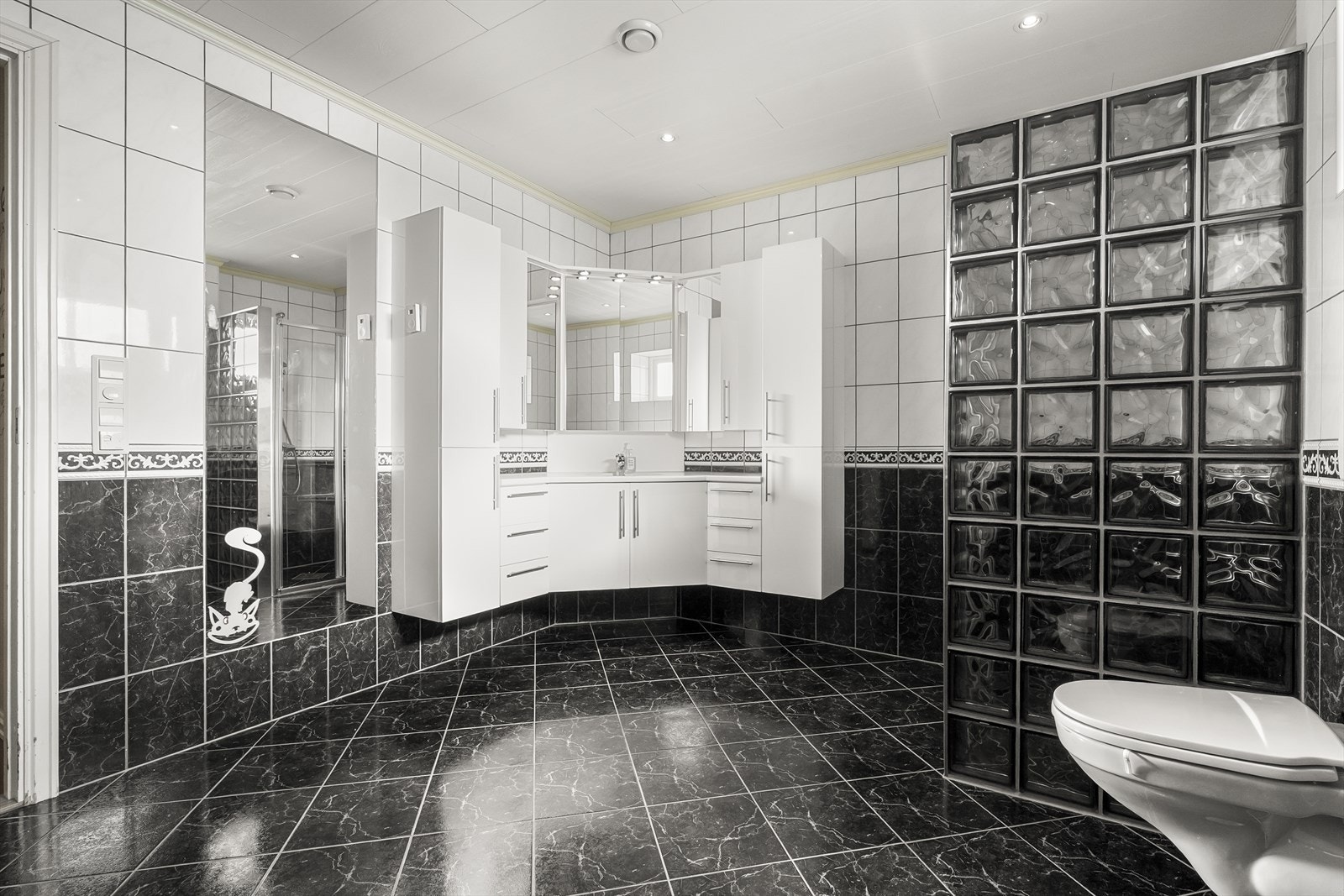 Heilflisa bad på hovudplan med dusjhjørne, vegghengt klosett og hjørne-innredning Galleribilde