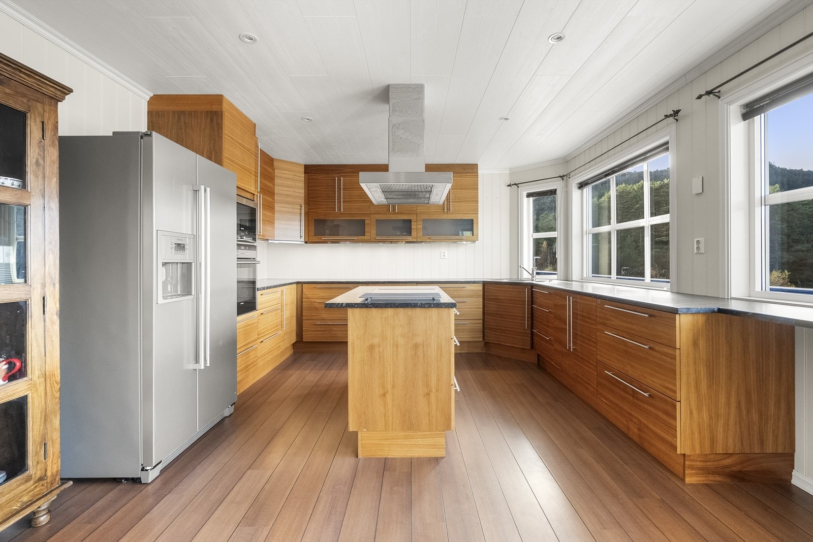 Separat kjøkken med ei stor innredning med mykje skap- og benkeplass, samt kjøkkenøy med koketopp Galleribilde