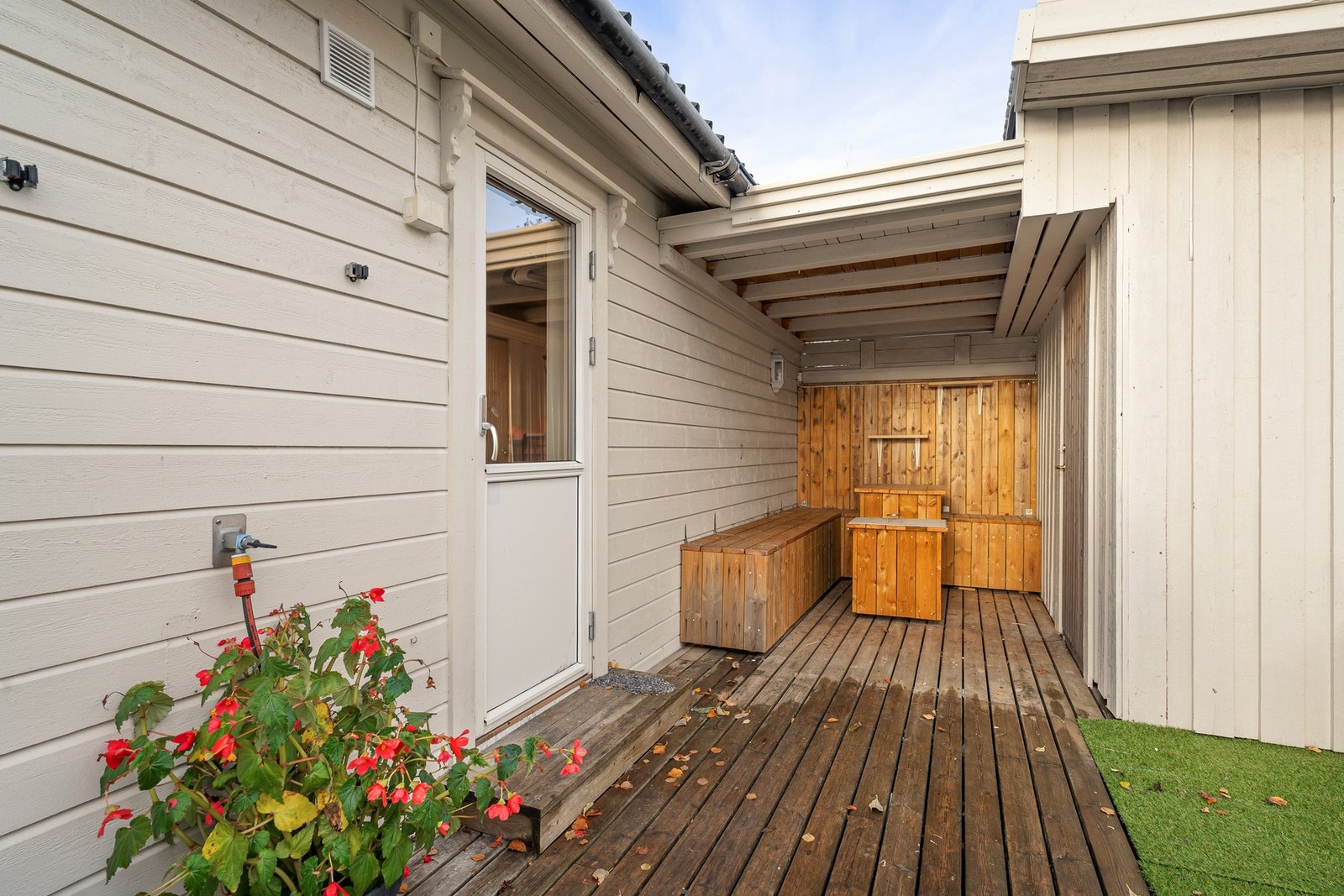 Lun uteplass med takoverbygg og plassbygde sittebenker, til høyre er det utebod Galleribilde