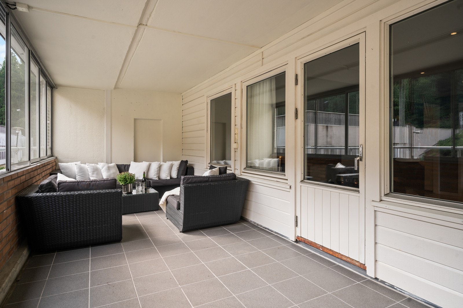 Gulvet på verandaen er klassisk flislagt. På varmere dager, kan man skyve vinduene til side, for å slippe inn mer luft Galleribilde