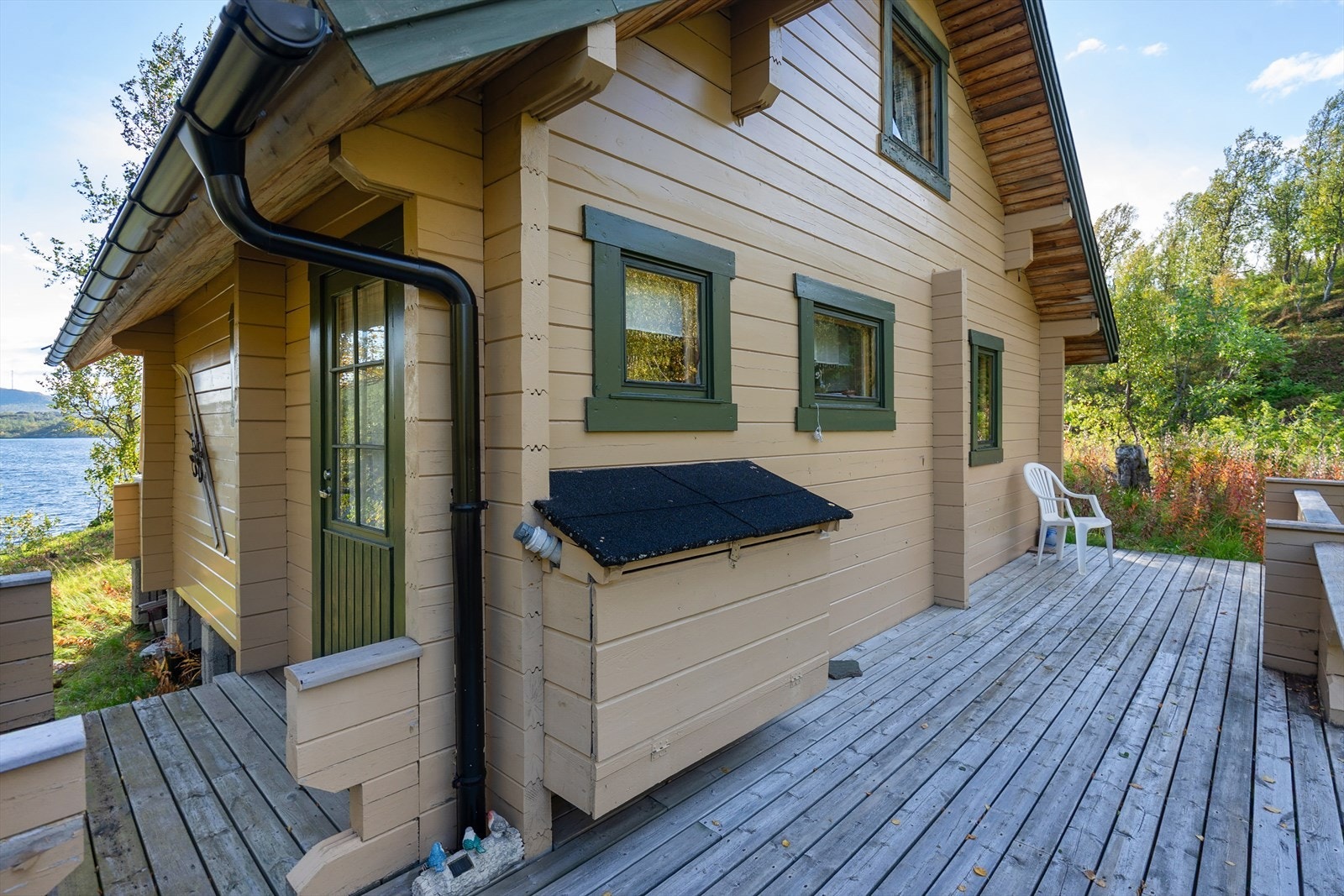 Hytten har en terrasse som strekker seg fra utgangen fra kjøkkenet og rundt i front av hytten Galleribilde