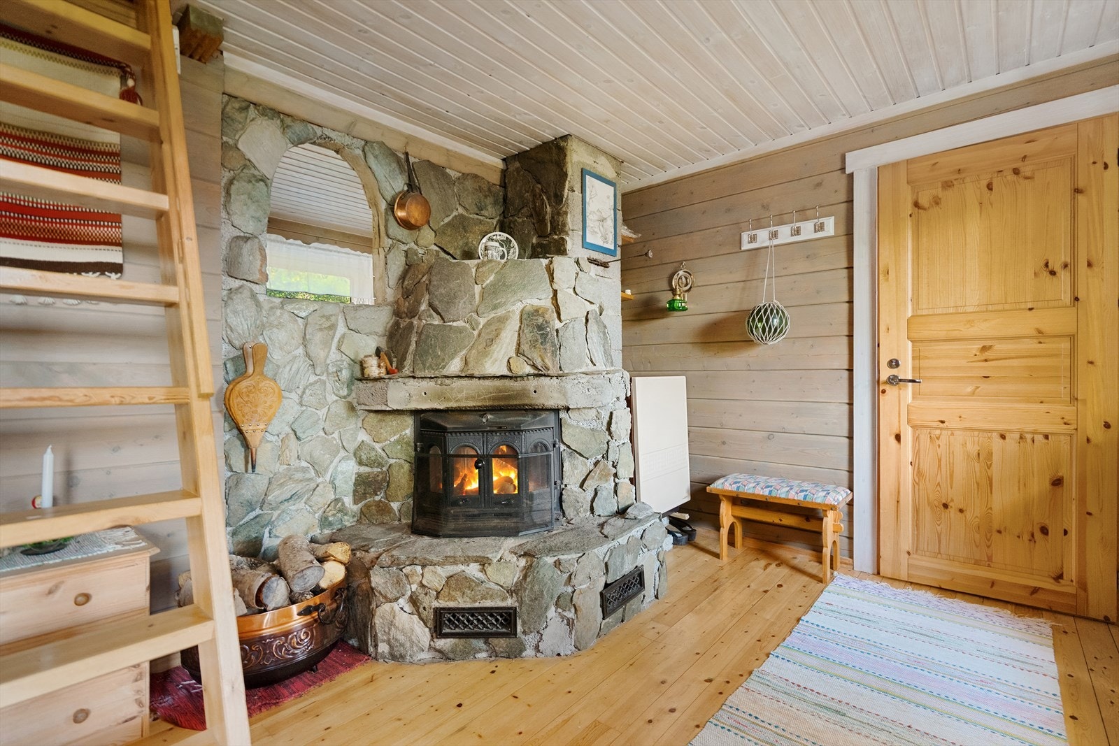 Lun stue med stor og sjarmerende natursteinpeis som skaper et lunt samlingspunkt i stua og gir ekte hyttefølelse Galleribilde